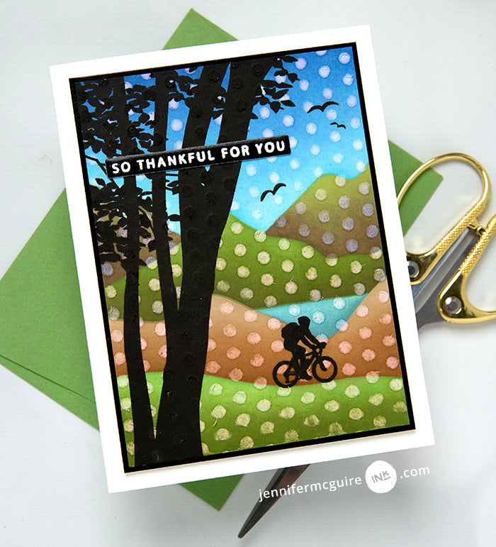 Gina K Designs Mountain Silhouettes Stamp with polka dot stencil over top. Sentiment reads "so thankful for you" while a cyclist rides on the hills in the background. | color-code:alt1