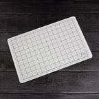 Tim Holtz Tonic Travel Glass Studio Mat 2634e Diagonal Mat on Dark Wood Background
