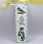 A bookmark with a floral border, featuring two blue-and-yellow birds, small blue hearts, and the phrase “His mercies are new every morning.” A yellow ribbon is tied at the top
