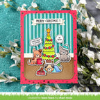A handmade Christmas greeting card featuring cartoon dogs by a decorated tree, with the text 'MERRY CHRISTMAS!' at the top, styled on a teal textured background with white flowers.
