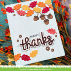 A handmade autumn-themed greeting card with 'MANY thanks' in raised glittery lettering, decorated with layered die-cut fall leaves and acorns. The card is displayed on a textured teal surface surrounded by dried orange and red leaves. | color-code:alt1