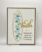A handmade greeting card featuring a cream background, a navy blue border, a gold oval frame, blue flowers, green leaves, and the word 'Faith' in gold script. 