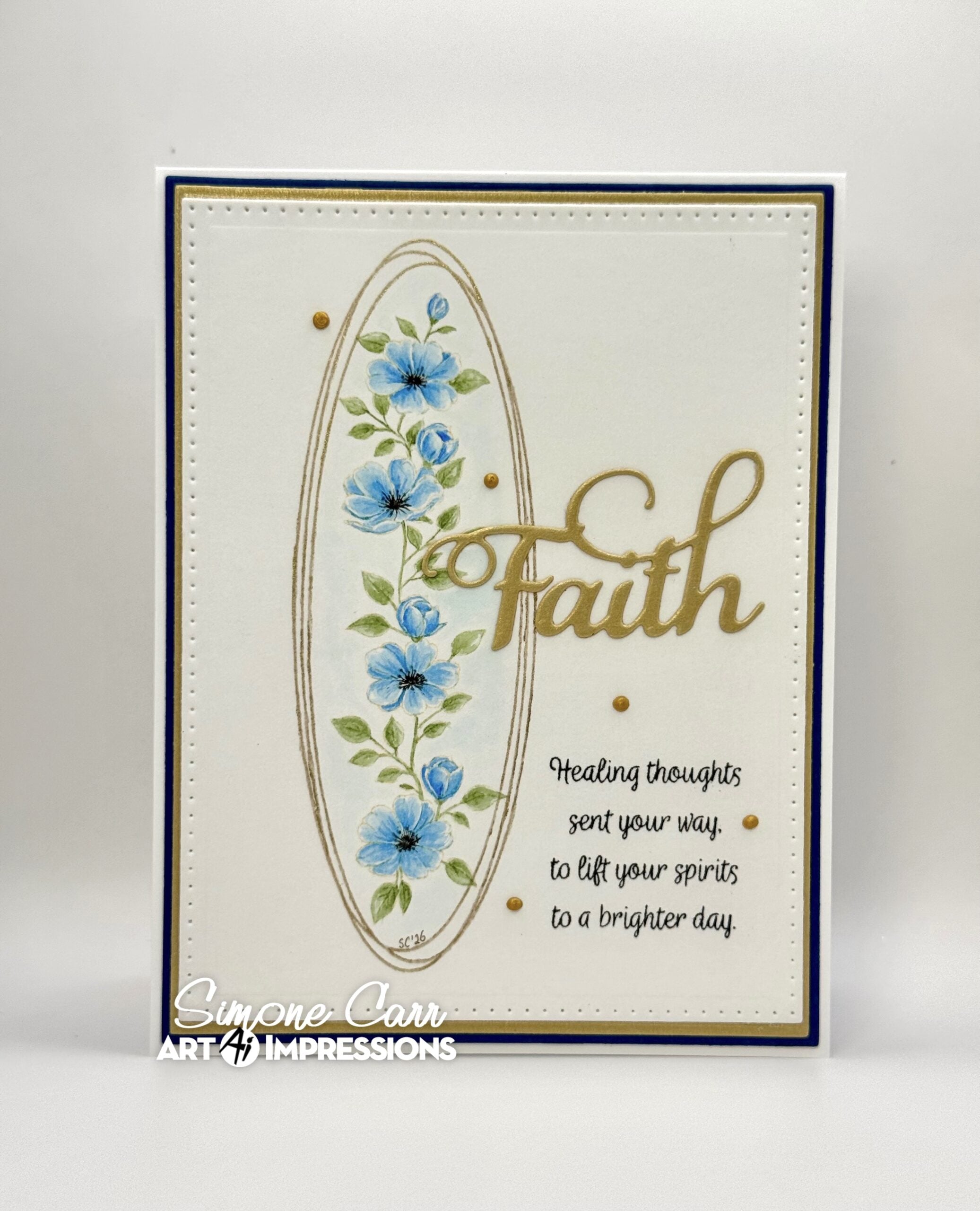 A handmade greeting card featuring a cream background, a navy blue border, a gold oval frame, blue flowers, green leaves, and the word 'Faith' in gold script. 