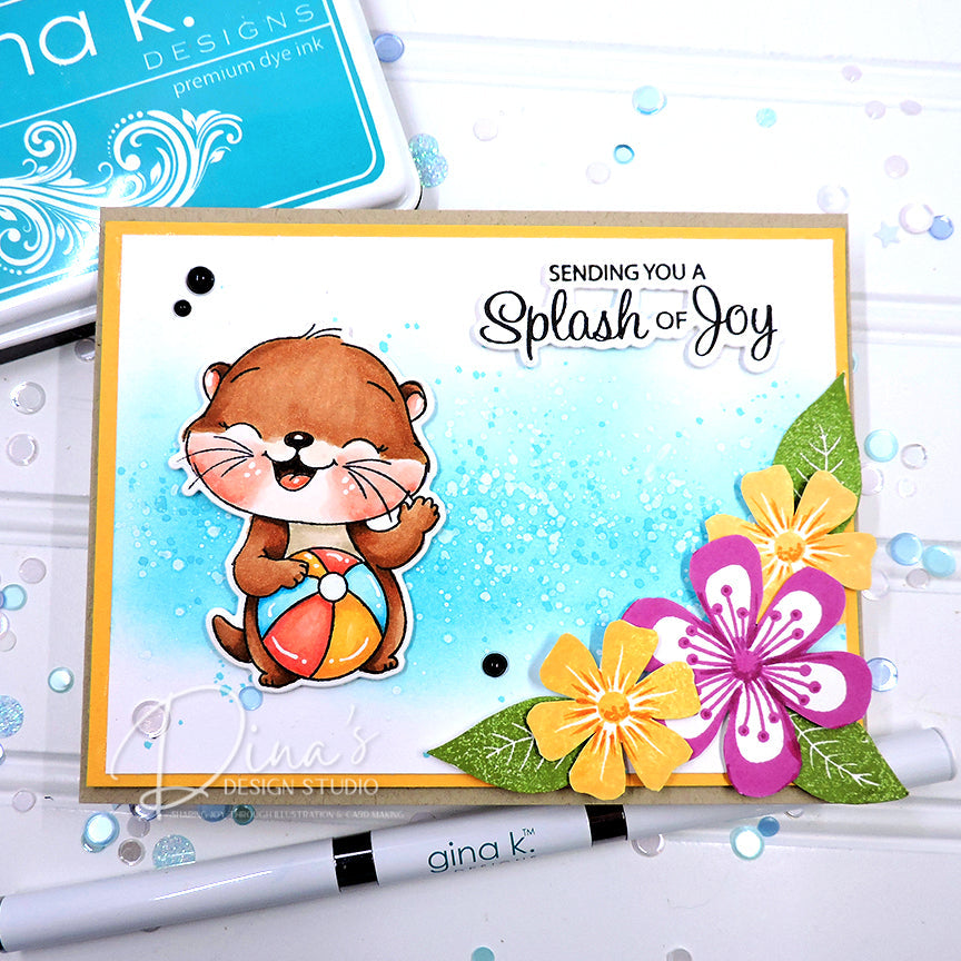 A handmade greeting card featuring a cute cartoon otter holding a beach ball, with layered paper flowers in yellow, pink, and green, and the text 'SENDING YOU A Splash of Joy'. A Gina K.
