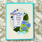 A handmade greeting card featuring a turquoise border, a striped cream background, an oval clear window, a blue bird, green leaves, blue hydrangea flowers, and a small light blue bow, displayed against a background of white flowers.