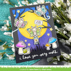 A handmade greeting card featuring a whimsical moth-themed illustration, displayed on a textured teal surface with white flowers. The card has a black border and shows three colorful butterflies, a large yellow moon, a snail under a purple mushroom, and the text 'i love you very moth'. | color-code:alt1