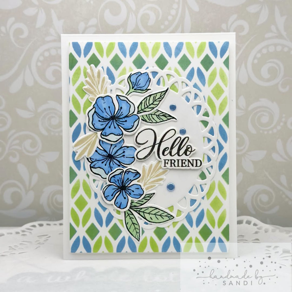 A handmade greeting card with a white base, featuring a green and blue geometric patterned background, layered die-cut floral elements in blue and green, and the words 'Hello FRIEND' in black script and block lettering. The card is displayed on a white surface against a gray patterned backdrop.