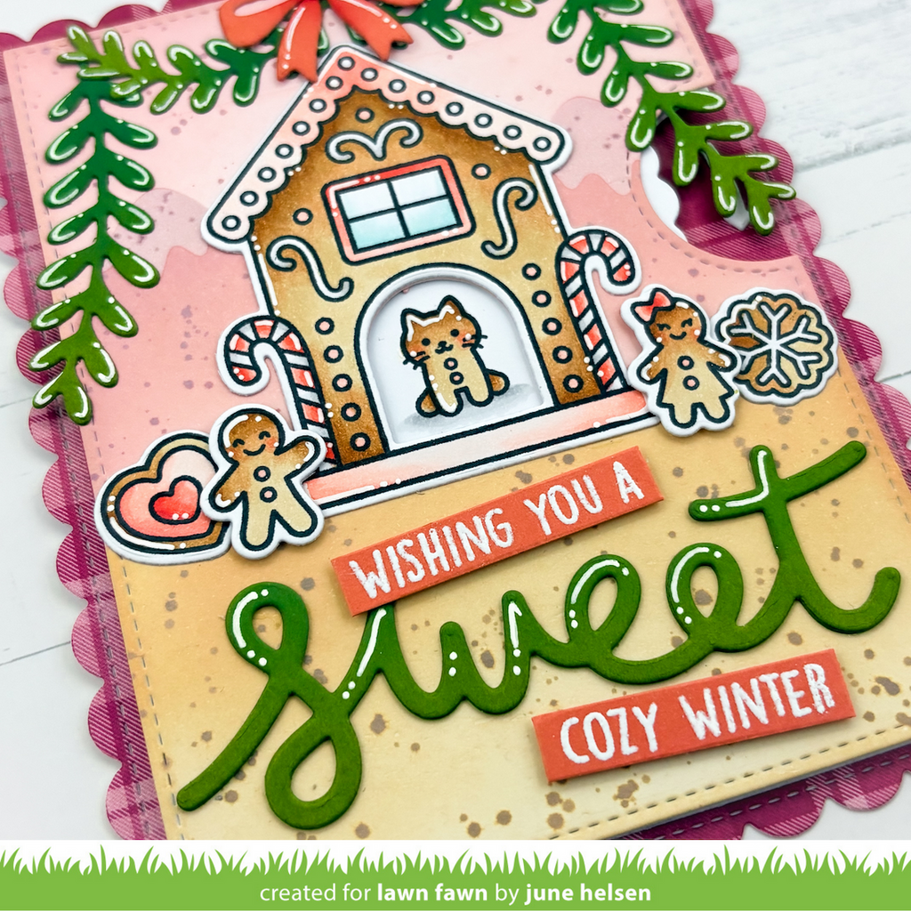 A handmade holiday greeting card featuring a gingerbread house with a cat, candy canes, gingerbread figures, and the text 'Wishing you a Sweet Cozy Winter' in green and orange lettering.