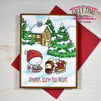 A handmade holiday greeting card from The Greeting Farm by Amy Young, featuring a winter scene with a snowman and a child on ice skates in front of a cozy house and evergreen trees. The card is displayed on top of a red envelope against a light wood background.