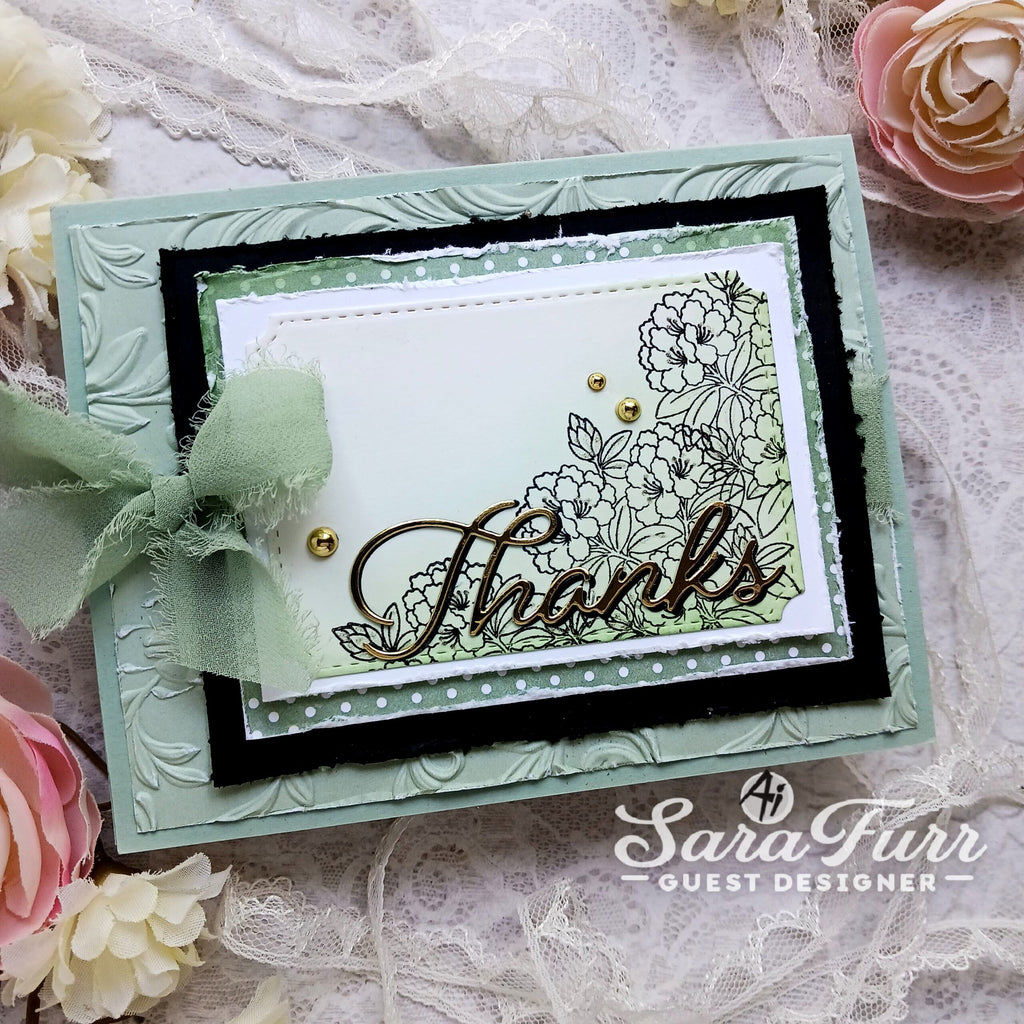 A handmade layered greeting card with embossed mint green borders, a black inner border, a white center panel, floral line art, and the word 'Thanks' in metallic script. A pale mint ribbon bow is attached on the left.