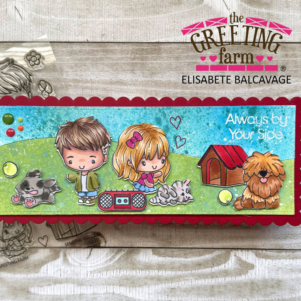 A rectangular handmade card with a scalloped red border and colorful cartoon-style illustrations of a boy, girl, dog, cat, and a small house, displayed on a whitewashed wood background. The card features the text 'Always by Your side' and is branded with 'the Greeting Farm' and 'Elisabete Balcavage' in the top right and bottom left.