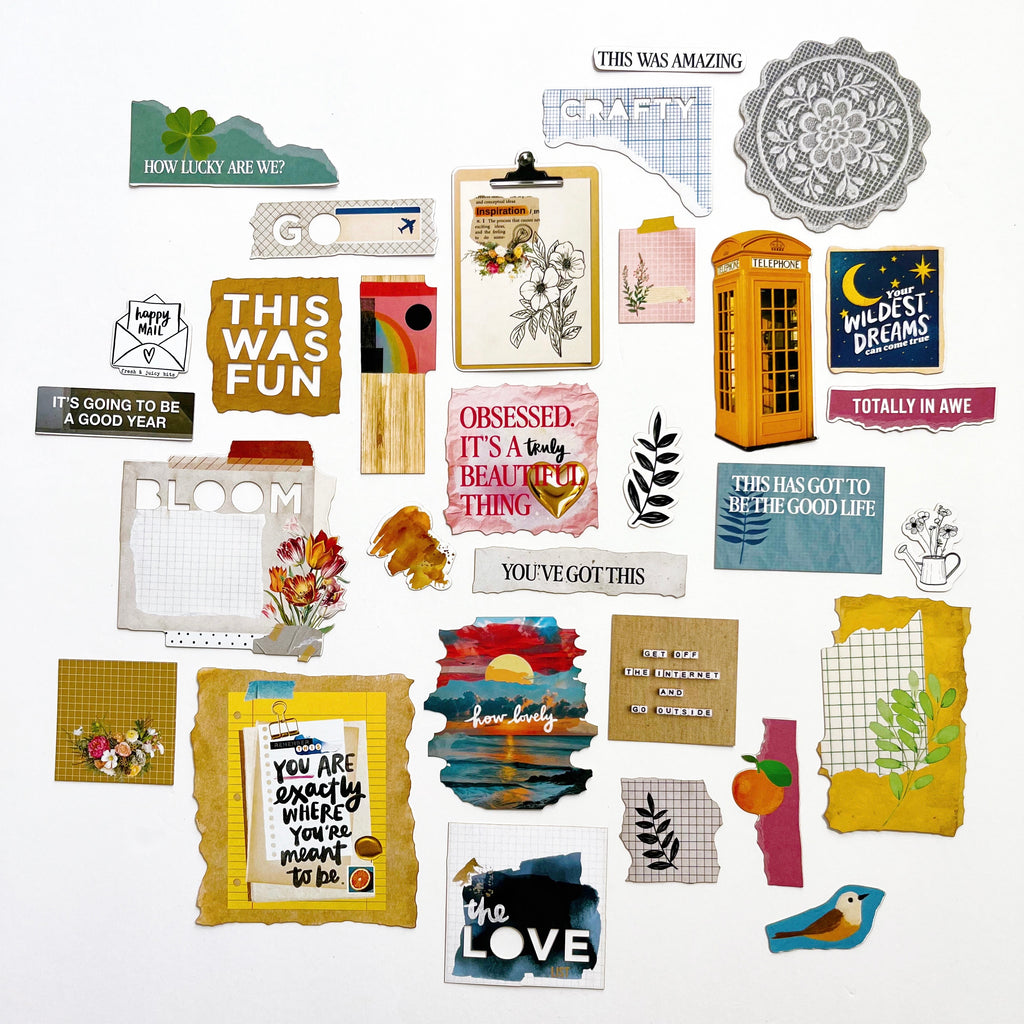 A flat-lay collection of various scrapbook paper sheets, stickers, and embellishments with inspirational quotes, floral designs, patterns, and colorful accents on a clean white background.