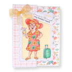 Card with a cartoon character in a floral dress and hat, holding a drink and a suitcase, with text 'Cruisin' through my Golden Years'.