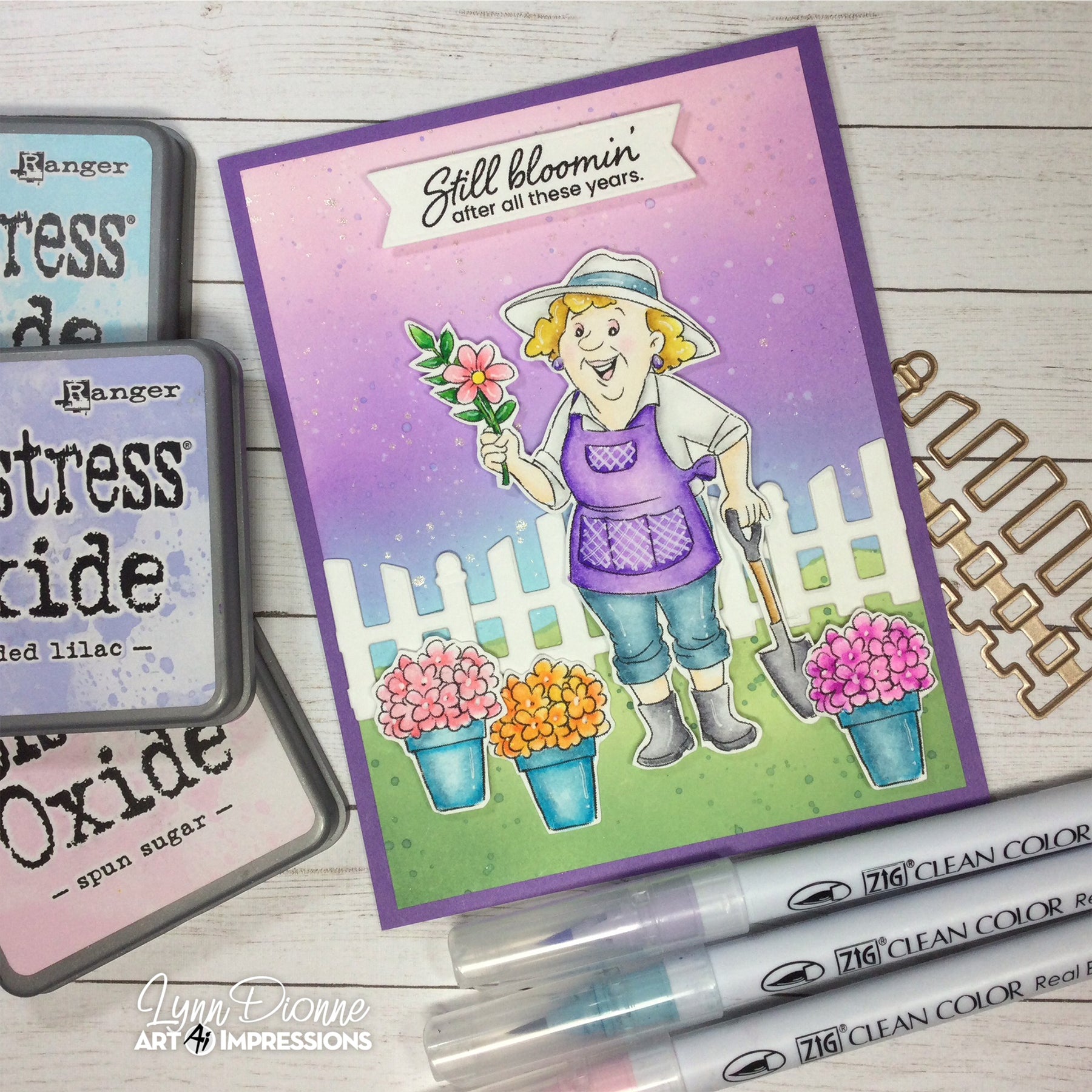 Card with a garden-themed illustration of a woman holding a flower, surrounded by gardening tools and ink pads.