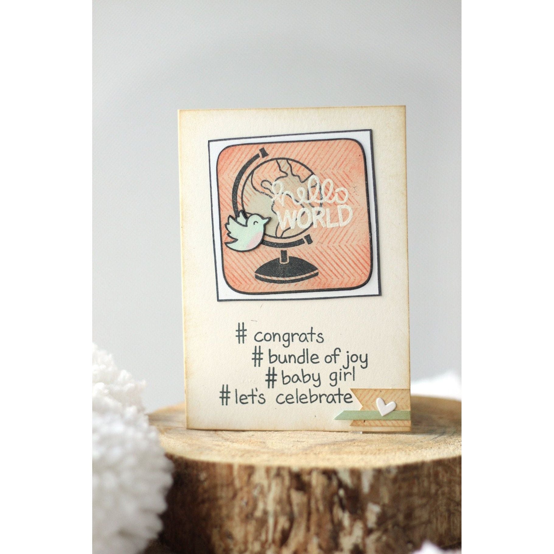 Baby shower card with 'Hello World' and '#congrats #bundle of joy #baby girl #let's celebrate' text on a wooden block.
