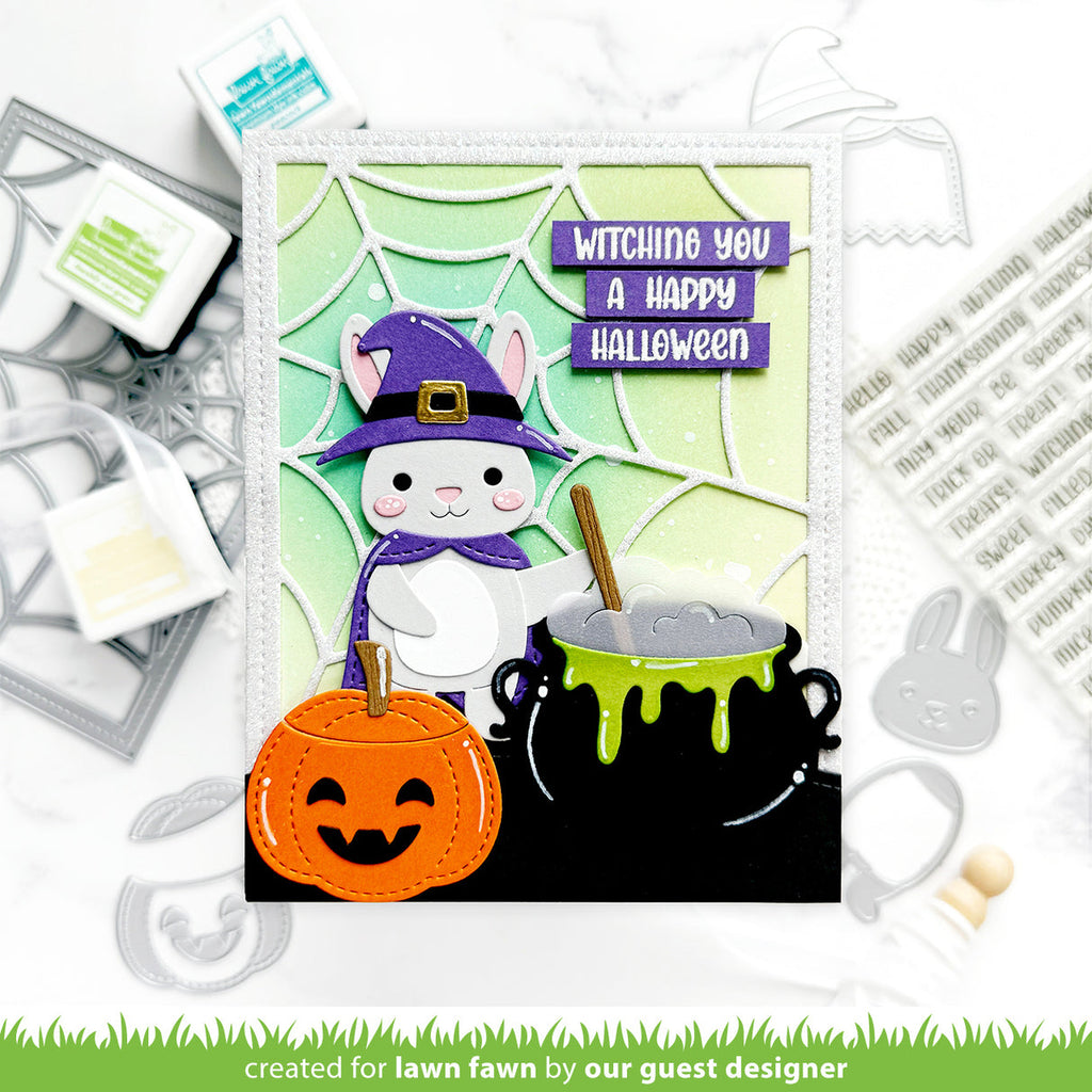Halloween-themed card with a cat in a witch hat, pumpkin, and cauldron, surrounded by crafting tools.