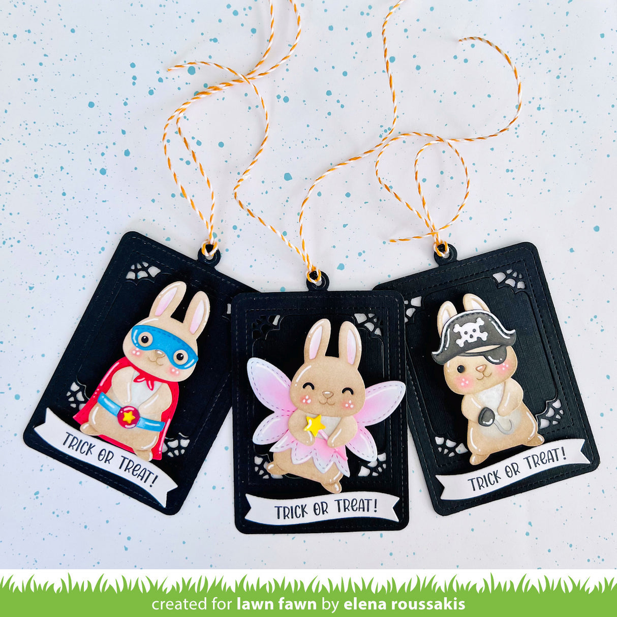 Three Halloween-themed rabbit figurines on black cards with decorative strings against a light blue background.