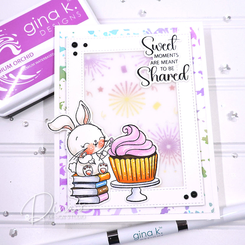 Card with a bunny and cupcake design, featuring the text 'Sweet moments are meant to be shared', with Gina K. Designs stamp and ink pad in the background.