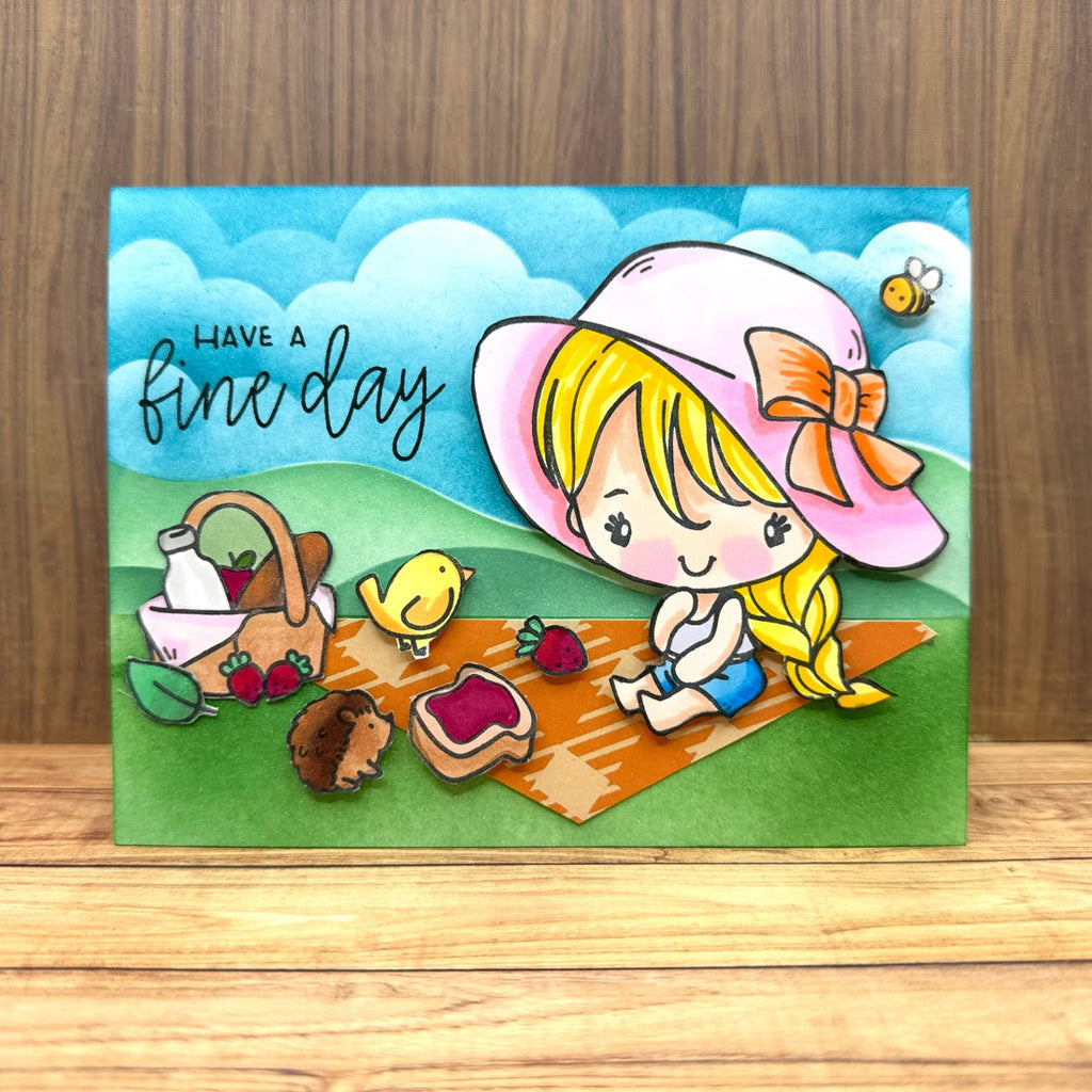 Card with a cartoon girl at a picnic, featuring text 'Have a fine day' on a wooden surface.