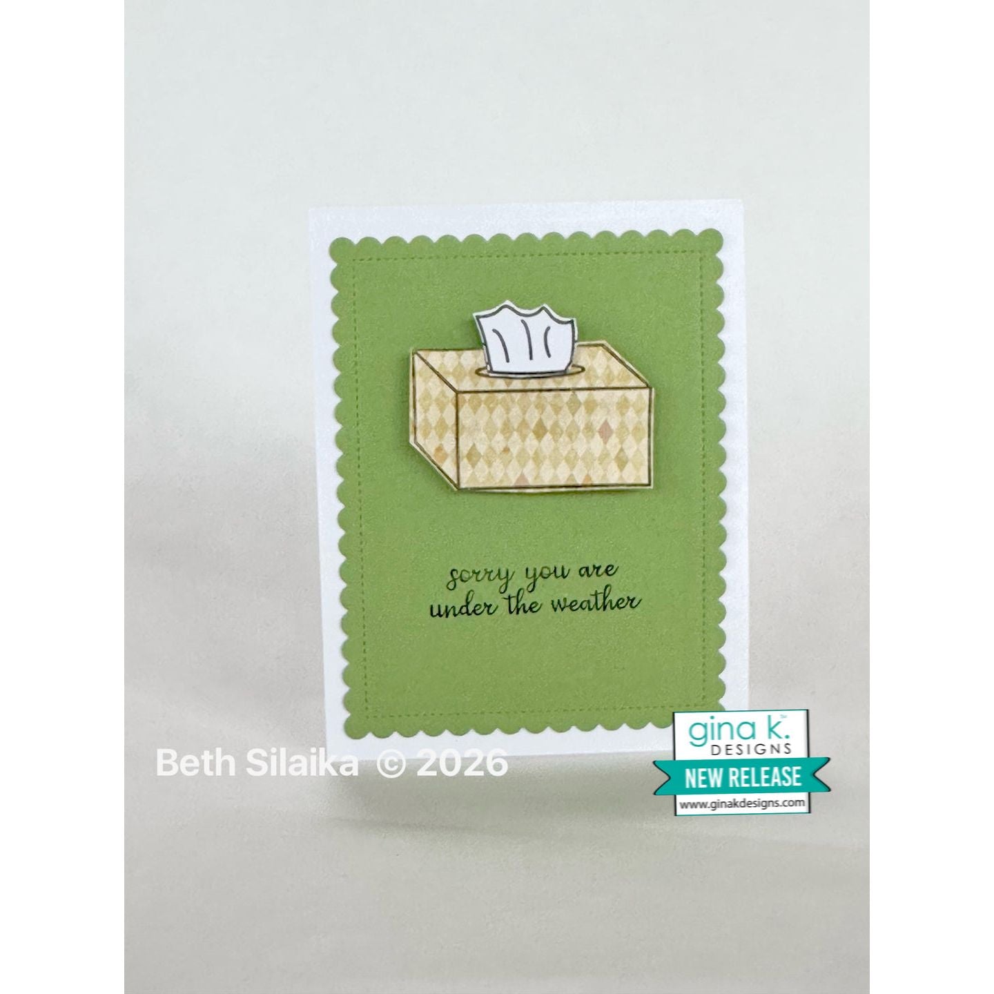 Card with a tissue box and 'sorry you are under the weather' text on a green background, featuring Gina K. Designs branding.