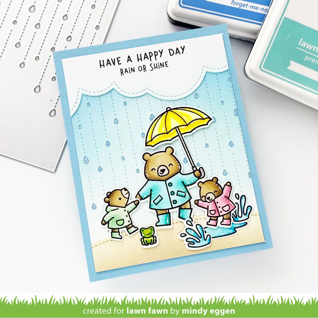 Card with bears in raincoats and an umbrella, text 'Have a happy day rain or shine', on a white background.