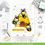 Card with cartoon bees and a beehive, featuring the text 'You're bee-utiful', surrounded by stamping supplies on a white background.