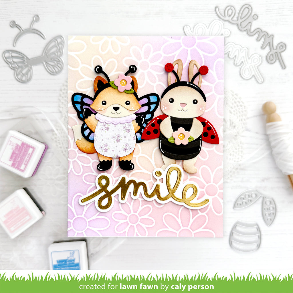 Card with cartoon fox and rabbit characters wearing insect costumes, surrounded by crafting supplies.