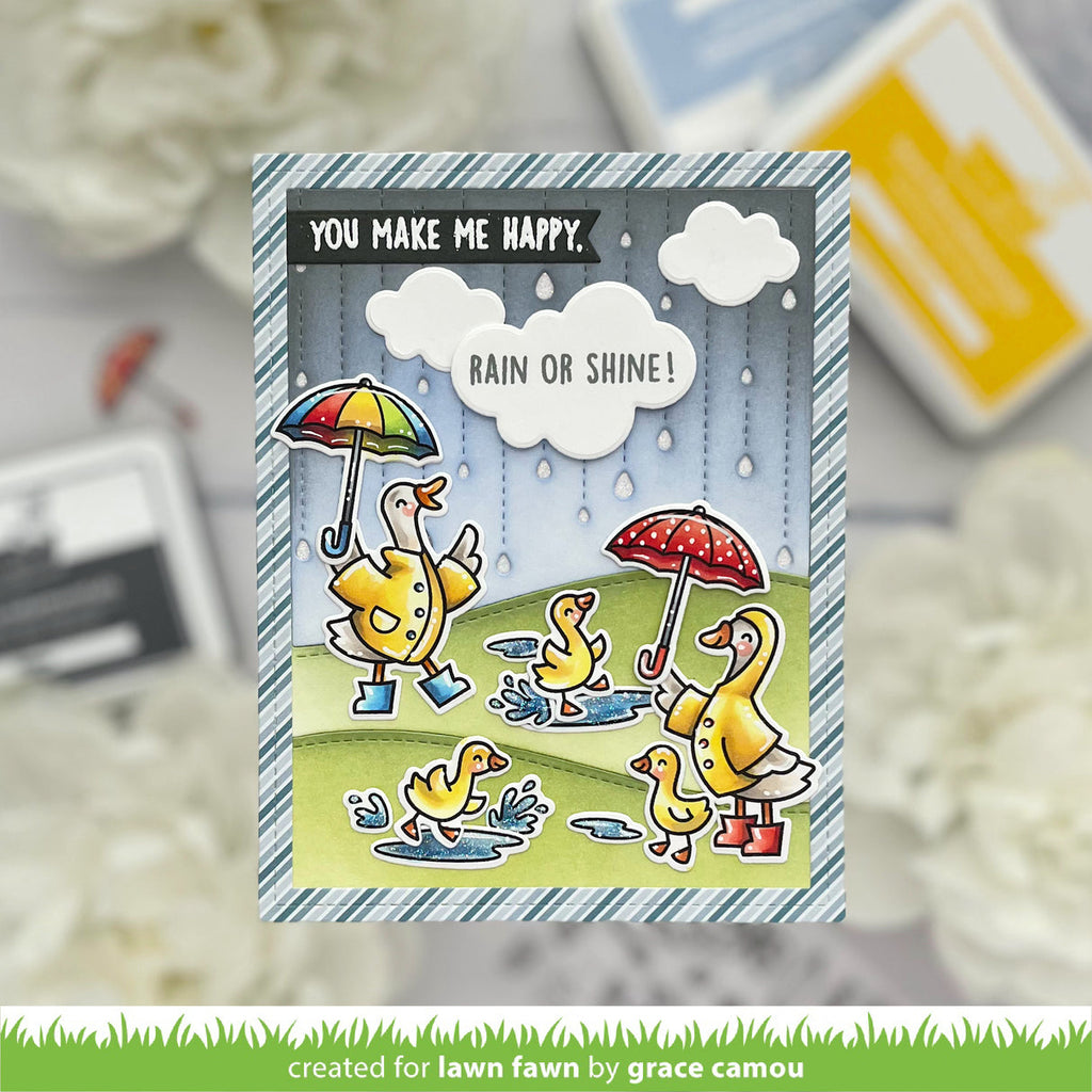 Card with ducks holding umbrellas and text 'You make me happy, rain or shine!' on a blurred background.