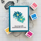 Card with floral design and text 'blooming with HAPPINESS FOR YOU' surrounded by Gina K. products on a grid background.
