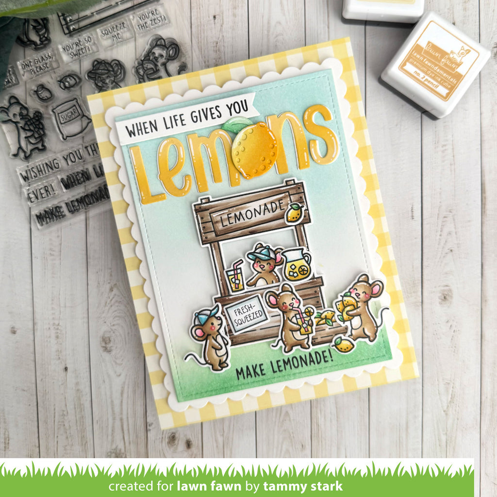 Card with lemon-themed design and cartoon mice, surrounded by stamping supplies on a wooden surface.
