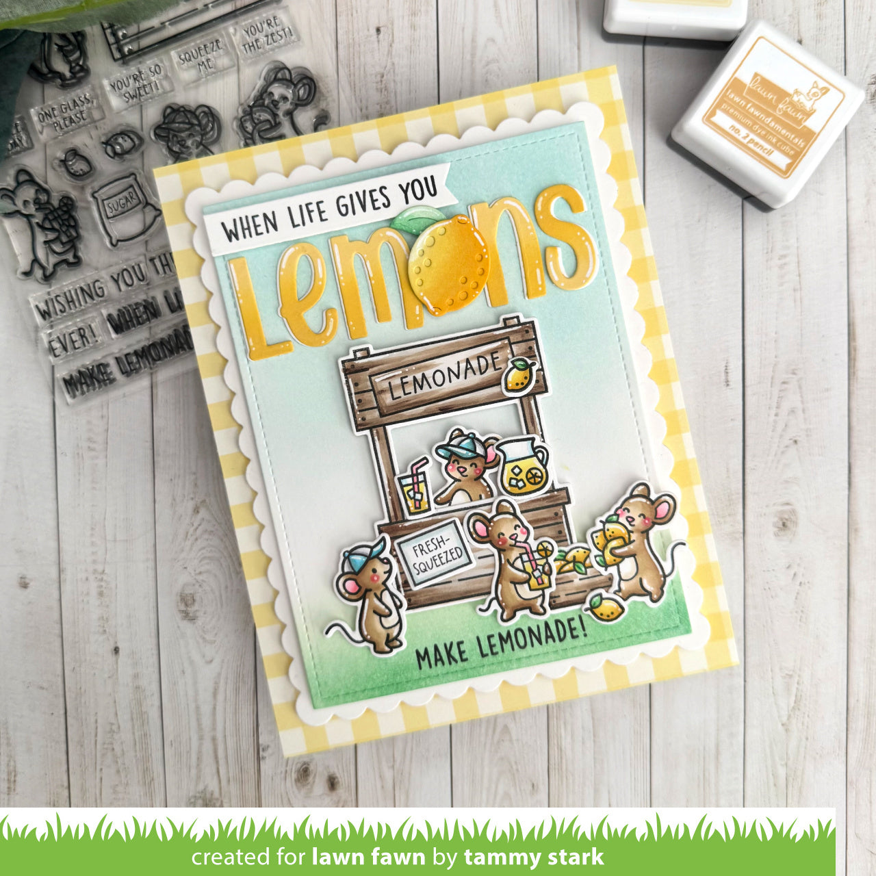 Card with lemon-themed design and cartoon mice, surrounded by stamping supplies on a wooden surface.