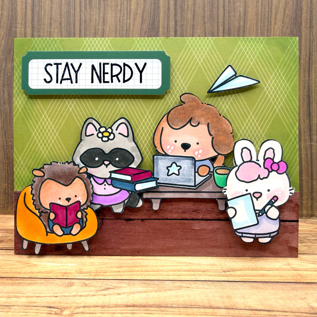 Cartoon animals studying with a laptop and books, on a green background with 'Stay Nerdy' text.