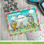 Colorful card with ducks and rainbow border on a wooden surface with stamping tools.