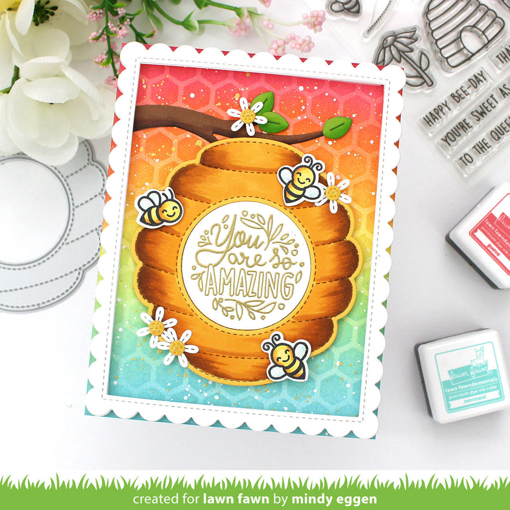 Colorful card with honeycomb design and bee illustrations, surrounded by stamping tools.