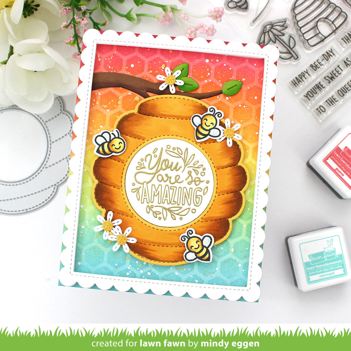 Colorful card with honeycomb design and bee illustrations, surrounded by stamping tools.
