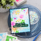 Colorful floral card with 'blooming with happiness for you' text on a decorative plate.
