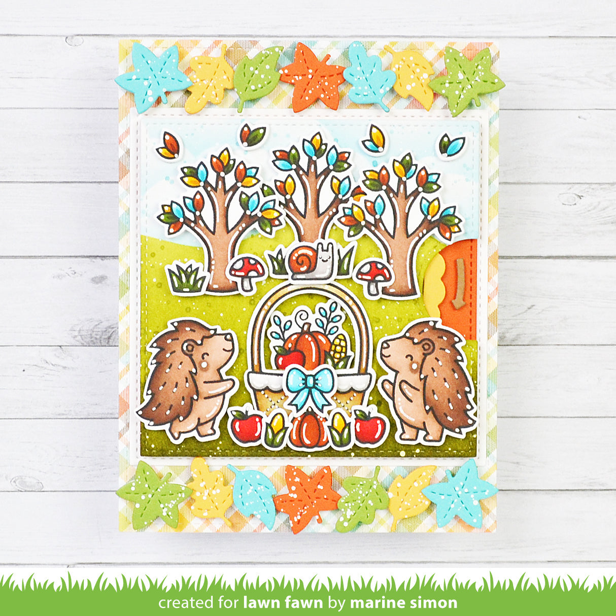 Colorful card with hedgehogs, trees, and autumn elements on a wooden background