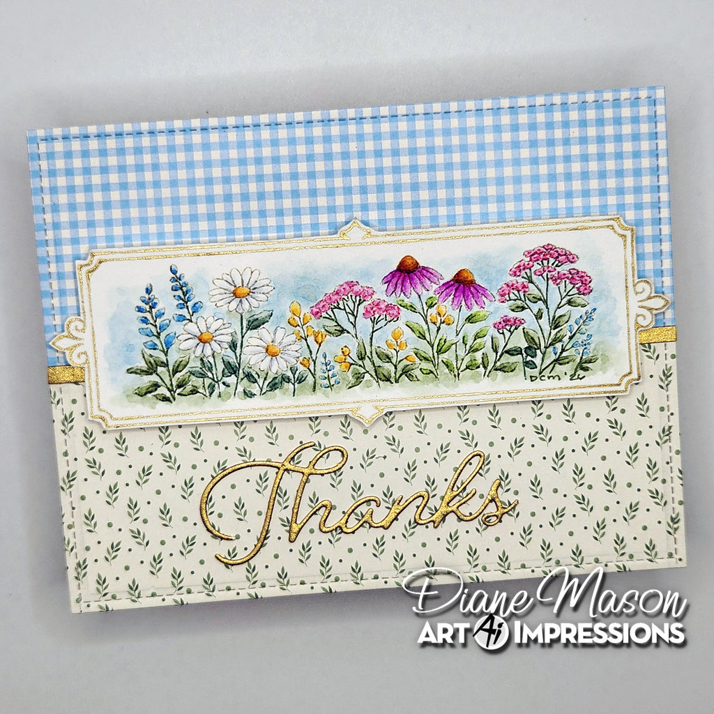 A handmade greeting card with a blue and white gingham patterned top section, a central floral illustration panel with pink, purple, yellow, and white flowers, and a lower cream section with green leaf print and gold foil script reading 'Thanks.'