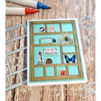 Card with decorative elements on a wooden surface with markers and die cuts.