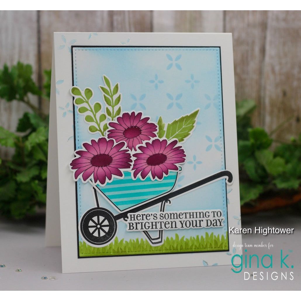 Greeting card with flowers and a wheelbarrow design, featuring 'gina k. DESIGNS' branding.