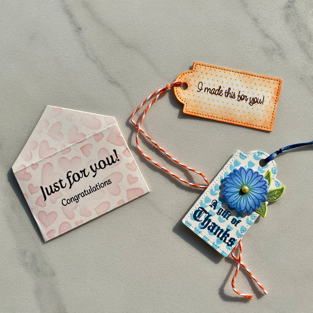 Three decorative gift tags with messages on a gray surface