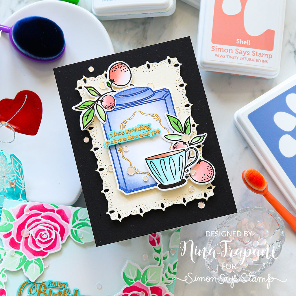 Card with tea-themed design on a crafting table with stamps and ink pads.