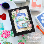 Card with tea-themed design on a crafting table with stamps and ink pads.