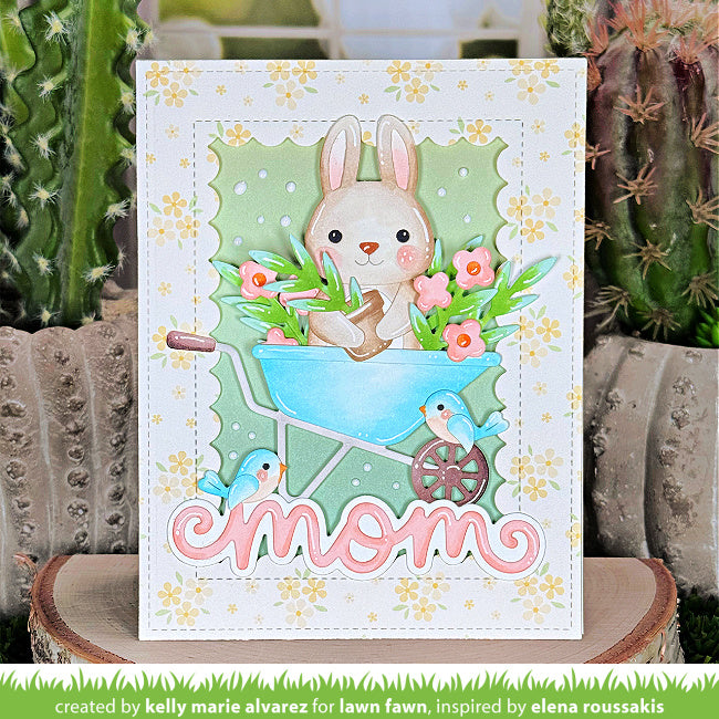 Greeting card with a bunny in a wheelbarrow and flowers, featuring the word 'mom'.