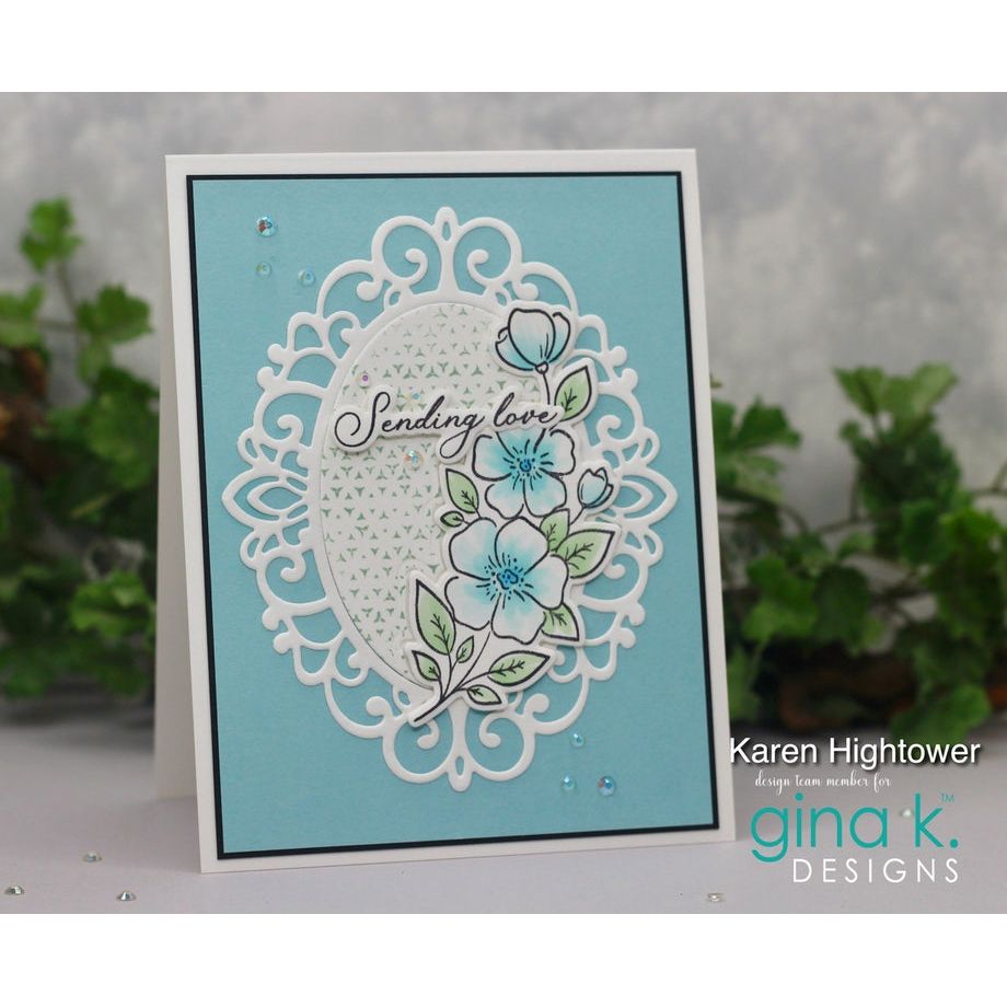 Greeting card with floral design and text 'Sending love' on a light blue background, featuring the brand 'gina k. Designs'.