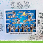Halloween-themed card with cartoon cats on brooms, surrounded by Halloween-themed stamps and dies.