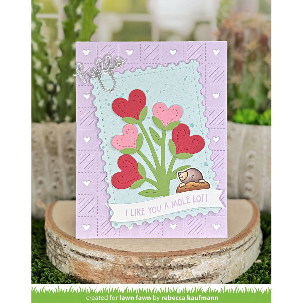 Card with heart design and text 'I like you a mole lot!' on a wooden block with plants in the background.