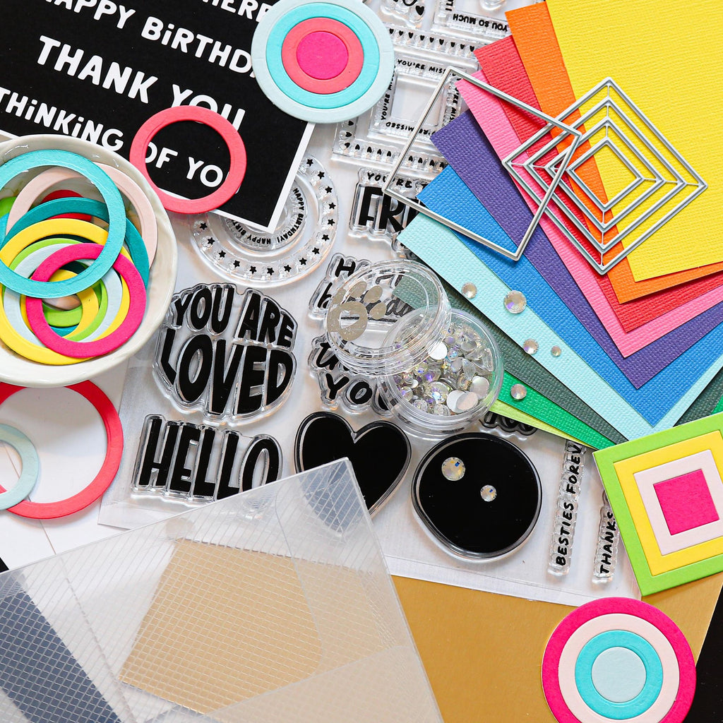 Collection of colorful craft supplies including paper, stickers, and decorative elements on a white background.