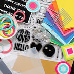 Collection of colorful craft supplies including paper, stickers, and decorative elements on a white background.