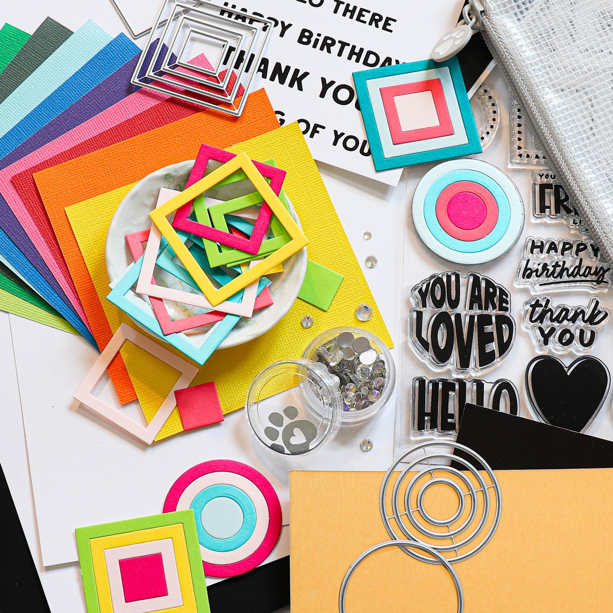 Colorful paper cutouts, stamps, and decorative items on a white surface